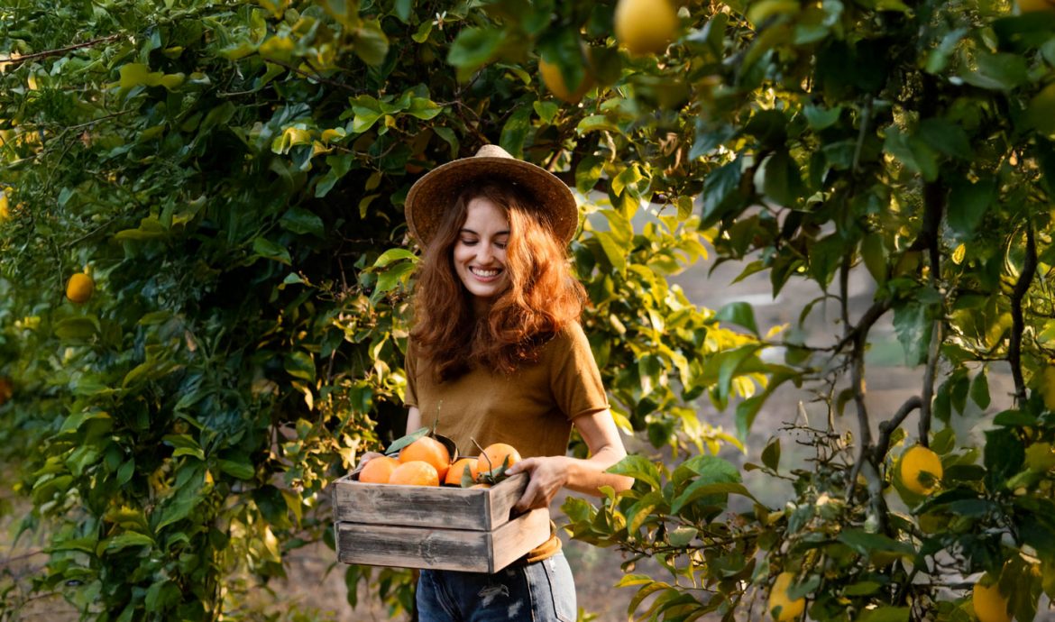 Femme qui porte une cagette d'oranges