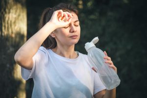 Femme qui a mal à la tête et qui boit de l'eau