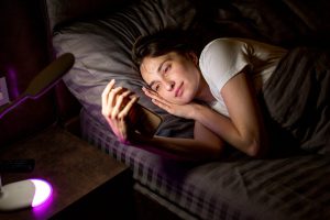 Femme qui est sur son téléphone dans son lit la nuit