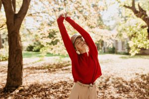 Jeune femme qui s'étire et prend le soleil en automne dans un parc